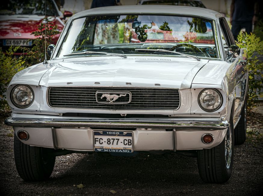 Front view of a classic white 1966 Ford Mustang, showcasing its iconic design in an outdoor setting.